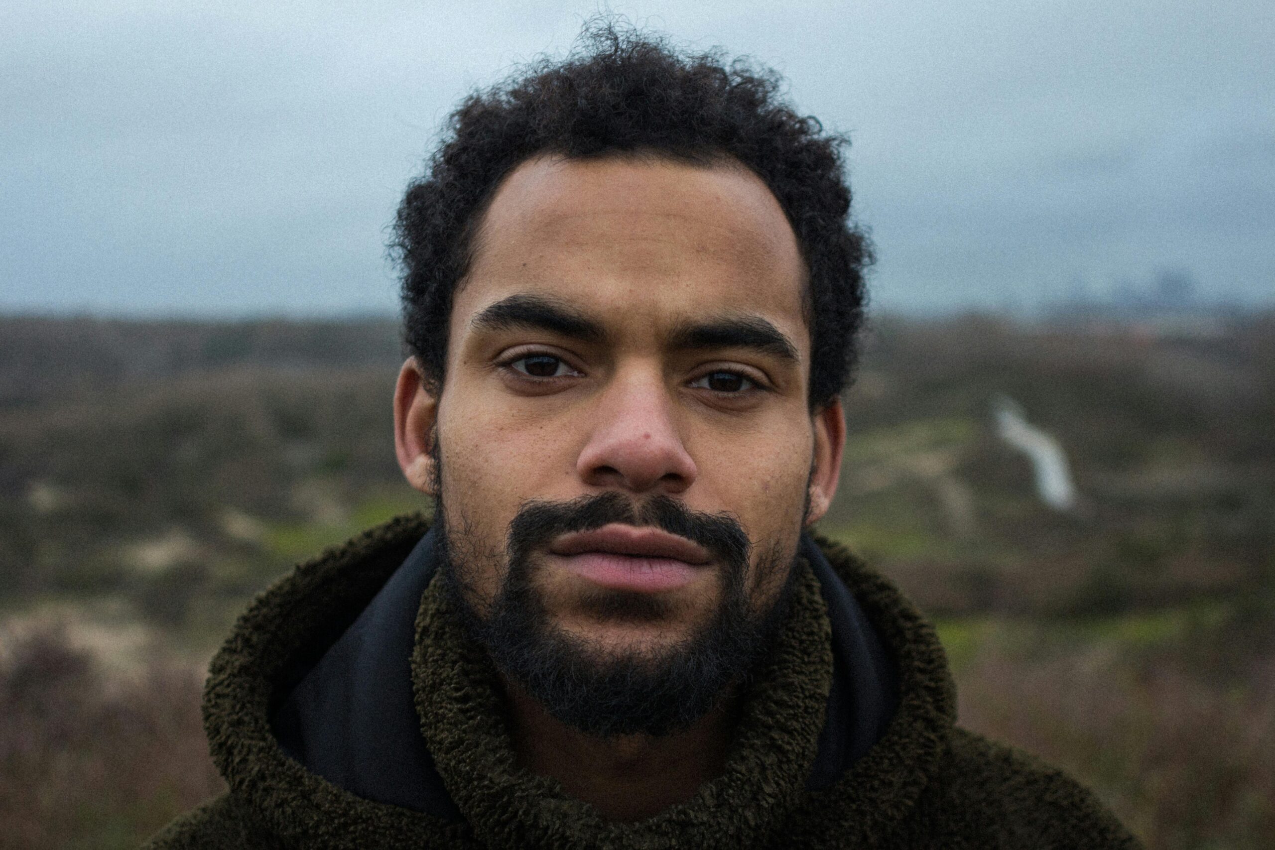 Portrait of a man with a beard outdoors in a winter landscape, conveying a moody atmosphere.
